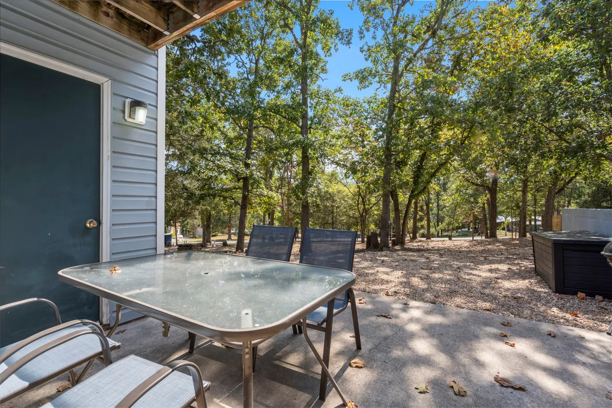 An exterior scene with a glass-topped table and outdoor chairs set among mature trees, creating a peaceful ambiance perfect for dining, socializing, or relaxing outdoors after a day of exploring Branson's attractions.