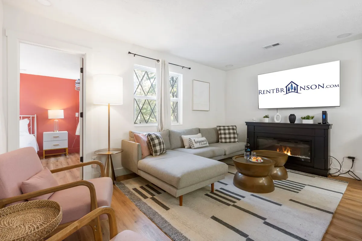 A cozy and inviting living area showcasing a plush sofa, a warm fireplace, a coffee table, and decorative pillows. The soft lighting and comfortable arrangement suggest a space perfect for gathering after a day of fun or enjoying restful moments during cooler seasons.