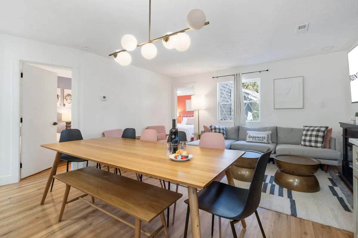 This image features a cozy dining area set adjacent to the living room, with a dining table ready for family meals and social gatherings. A decorative light fixture and inviting decor enhance the warm, welcoming mood. The space is ideal for shared feasts, game nights, or festive celebrations.
