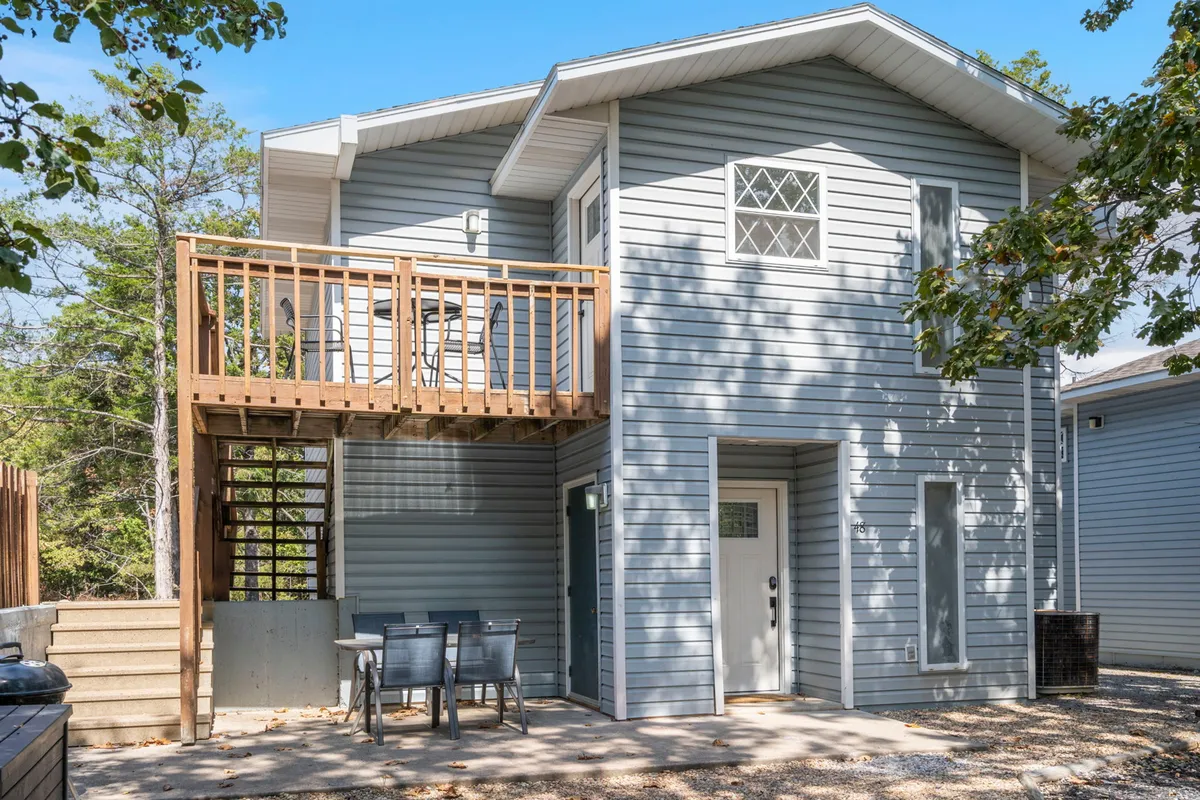 A casual outdoor seating area on a balcony, complete with chairs and a table, positioned near the entrance door. The area is ideal for socializing, enjoying the fresh air, or appreciating sunset views.